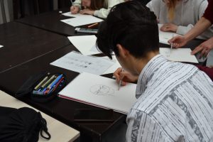 Blick über die Schulter eines Jugendlichen, der ein Manga Gesicht zeichnet