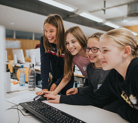 Vier Mädchen schauen gemeinsam auf einen Computerbildschirm