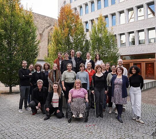 Gruppenbild mit Männern und Frauen im Innenhof vor einem Baum